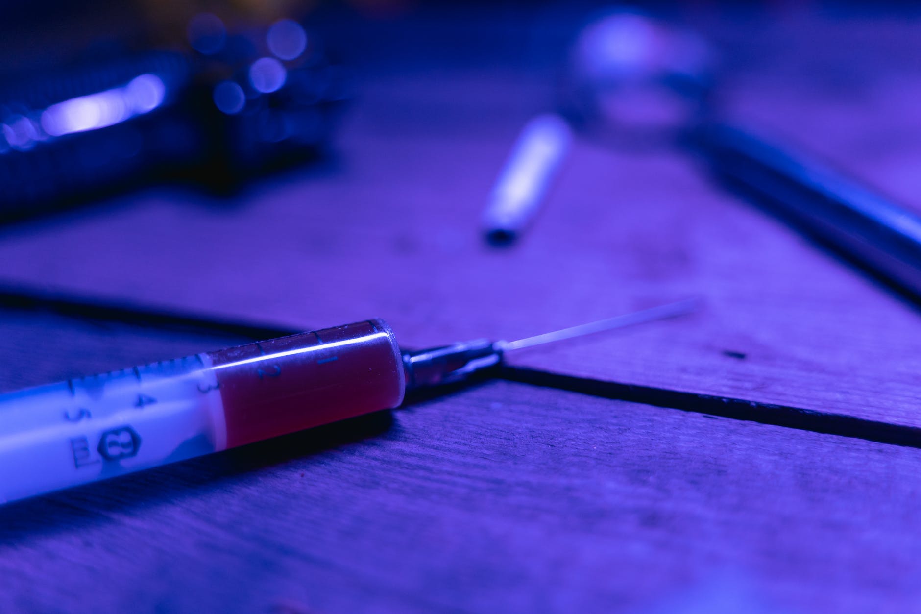 a syringe with brown chemical on a wooden table